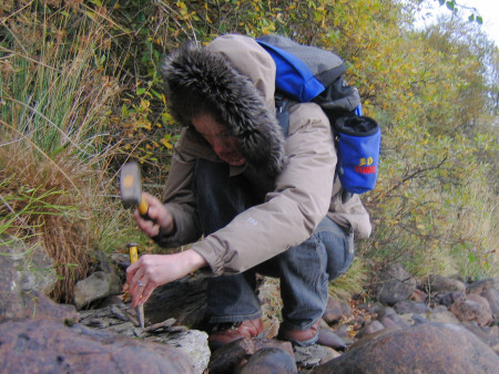 Lucinda Shepherd extracting a fossil from a rock at the River Brora